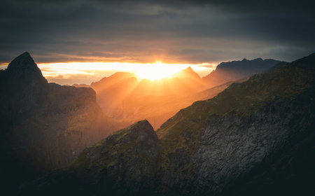 A beautiful scene of mountains at sunset with dark clouds and warm light.