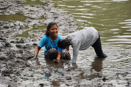 People fishing on gropyok iwak. Gropyok iwak means festival fishing together using traditional toolsのeditorial素材