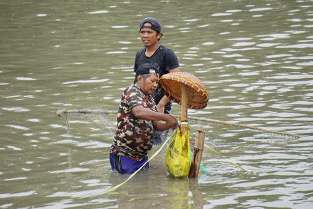 People fishing on gropyok iwak. Gropyok iwak means festival fishing together using traditional toolsのeditorial素材