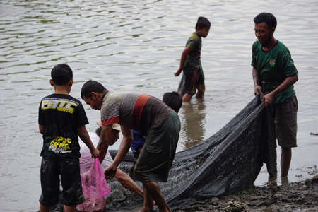 People fishing on gropyok iwak. Gropyok iwak means festival fishing together using traditional toolsのeditorial素材