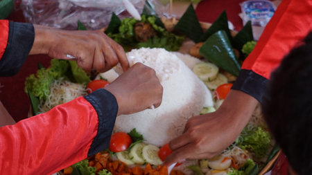 Chef serving nasi tumpeng (cone rice) served with urap-urap (Indonesian salad), fried chicken and noodles. Nasi tumpeng is usually served at birthday parties or Thanksgivingの写真素材
