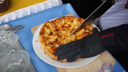 The chefs serving golden brown pizza for the customer, looks so delicious