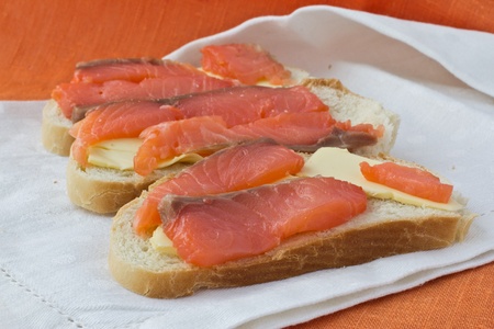 3 sandwiches with butter and salmon lying on white   linen napkin の写真素材