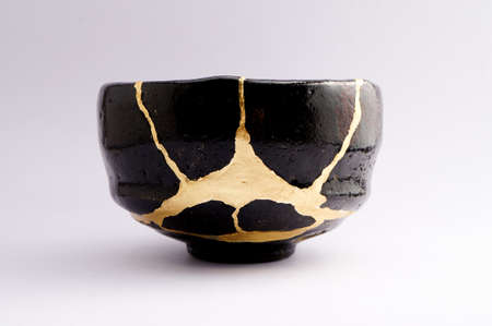 Kintsugi tea ceremony bowl. Gold cracks restoration on old Japanese pottery restored with the antique restoration technique The unique beauty of imperfections.の写真素材