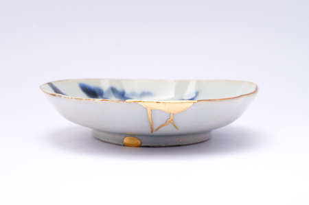 Kintsugi plate. Gold cracks restoration on old Japanese pottery restored with the antique restoration technique The unique beauty of imperfections.の写真素材