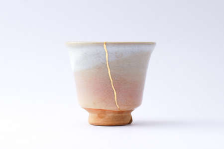 Kintsugi sake cup. Gold cracks restoration on old Japanese pottery restored with the antique restoration technique The unique beauty of imperfections.の写真素材