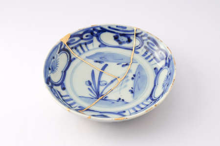 Kintsugi plate. Gold cracks restoration on old Japanese pottery restored with the antique restoration technique The unique beauty of imperfections.の写真素材