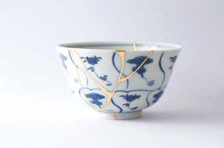 Kintsugi tea ceremony bowl. Gold cracks restoration on old Japanese pottery restored with the antique restoration technique The unique beauty of imperfections.の写真素材