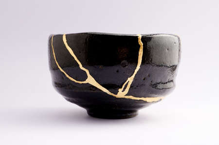 Kintsugi tea ceremony bowl. Gold cracks restoration on old Japanese pottery restored with the antique restoration technique The unique beauty of imperfections.の写真素材