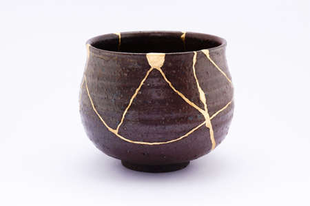 Kintsugi tea ceremony bowl. Gold cracks restoration on old Japanese pottery restored with the antique restoration technique The unique beauty of imperfections.の写真素材