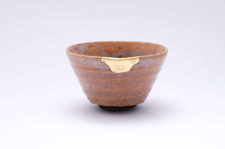 Kintsugi sake cup. Gold cracks restoration on old Japanese pottery restored with the antique restoration technique The unique beauty of imperfections.の写真素材