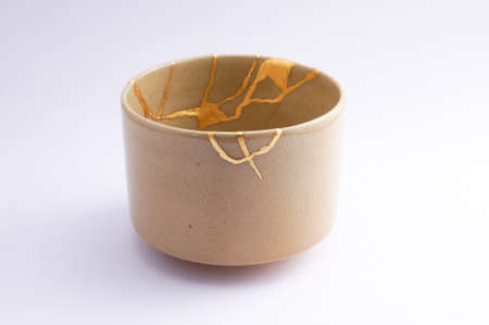 Kintsugi Japanese tea ceremony bowl. Gold cracks restoration on old Japanese pottery restored with the antique Kintsugi restoration technique. The beauty of imperfections.の写真素材