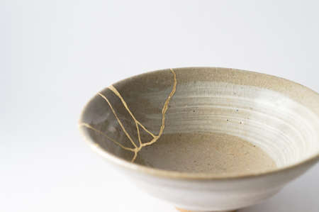 Kintsugi pottery. Gold cracks restoration on old Japanese pottery restored with the antique Kintsugi restoration technique. The beauty of imperfections.の写真素材