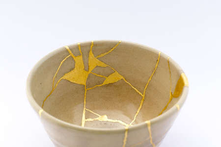 Kintsugi Japanese tea ceremony bowl. Gold cracks restoration on old Japanese pottery restored with the antique Kintsugi restoration technique. The beauty of imperfections.の写真素材