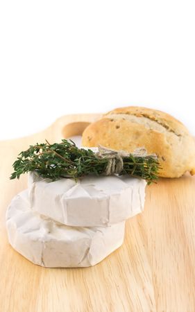 Cheese with white mold and a bundle of herbs on cutting boardsの写真素材