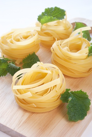 raw fettuccine on the cutting board with fresh herbsの写真素材