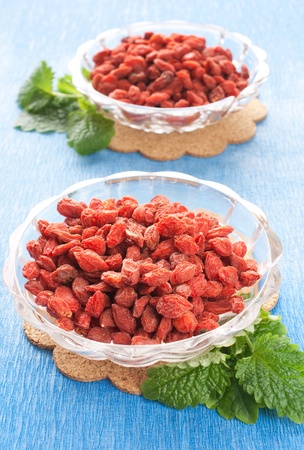 full bowl of red dried goji berries with fresh herbsの写真素材