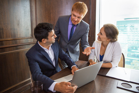 Male executive manager standing in conference room, pointing to laptop screen and explaining business ideas to his team. Teamwork conceptの写真素材