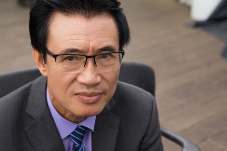 Close up portrait of serious Asian senior businessman looking at cameraの写真素材