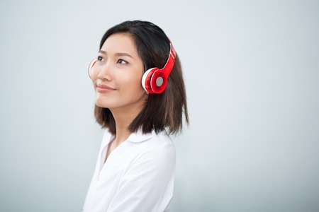 Closeup of content pretty young Asian woman wearing headphones and listening to musicの写真素材