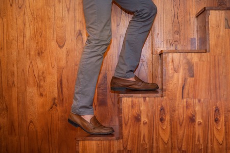 Cropped image of legs of man climbing wooden stairs. Side view.の写真素材