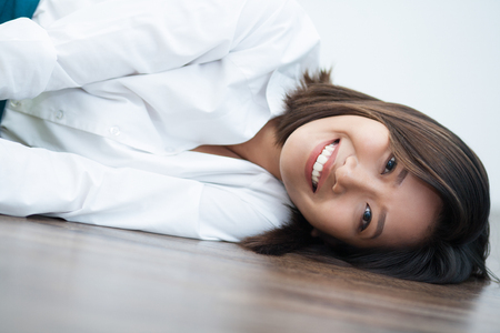 Happy Vietnamese business lady lying on floor and looking at camera on floor. Portrait of smiling young woman resting or relaxing on floor. Business conceptの写真素材