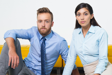 Two serious young business people looking at camera. Portrait of multiethnic businessman and businesswoman working as team. They are managers. Business conceptの写真素材
