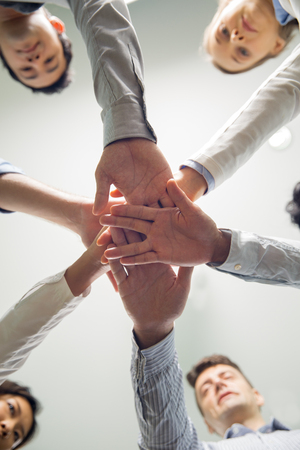 Below view of multiethnic business team stacking hands showing support, success and corporate spiritの写真素材