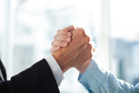 Close-up of two clasped hands of businessmen as sign of strong partnership or team. Unrecognizable men in arm wrestling gesture. Business union conceptの写真素材