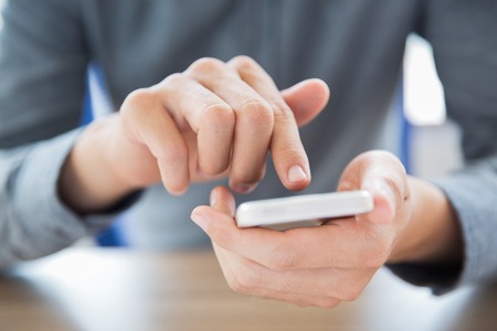 Close-up of male hands holding smartphone and touching screen. Businessman texting message or...