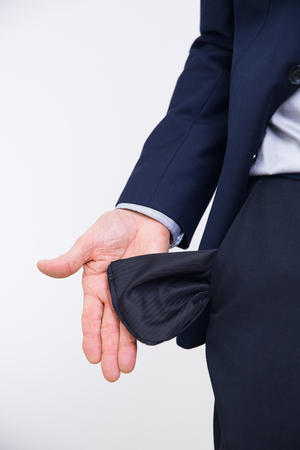Close-up of hand of senior businessman in suit turning pocket of his trousers inside out and showing it empty. Crisis, unemployment, bankruptcy conceptの写真素材