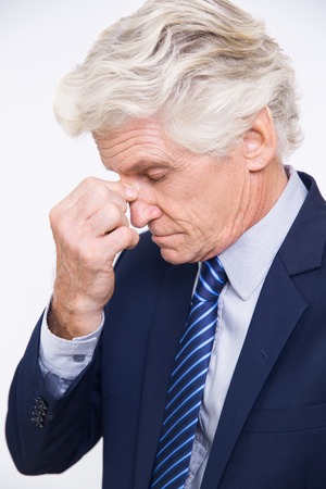Portrait of depressed senior Caucasian man wearing suit rubbing eyes. Elderly man having problem or headacheの写真素材