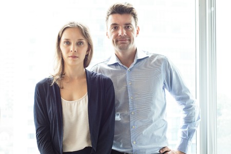 Two Male and Female Colleagues Standing at Windowの写真素材
