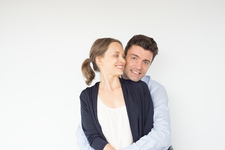 Smiling Young Man Embracing Girlfriend Tightlyの写真素材