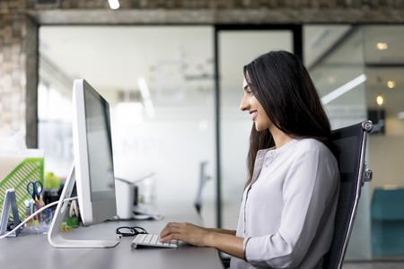 Smiling young businesswoman typing on computerの写真素材