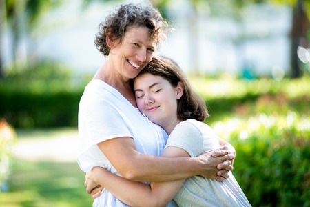 Smiling senior mother embracing teenage daughter