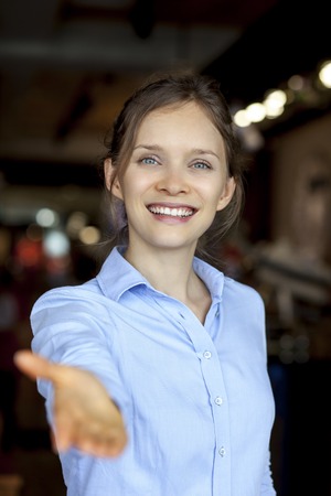Cheerful businesswoman reaching hand to cameraの写真素材