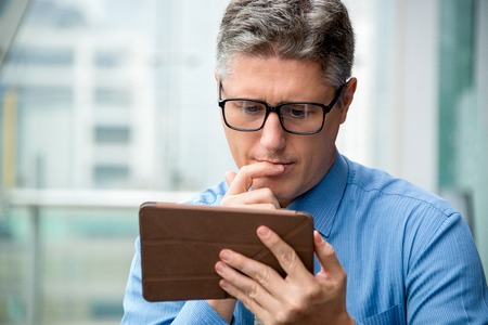 Closeup of Thoughtful Business Man Using Tablet