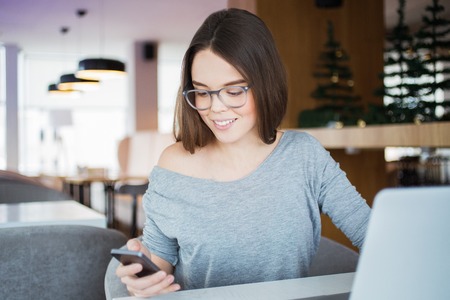 Smiling young woman texting message on smartphoneの写真素材