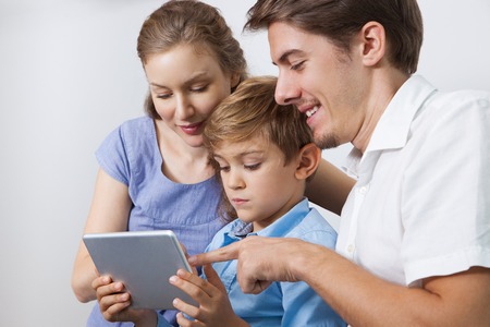 Smiling parents showing touchpad to little son