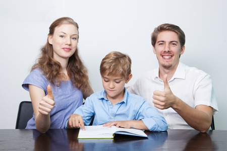Mom, Dad and Son Reading Book With Thumbs Upの写真素材