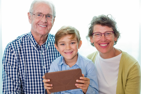 Cheerful grandparents and boy with gadget