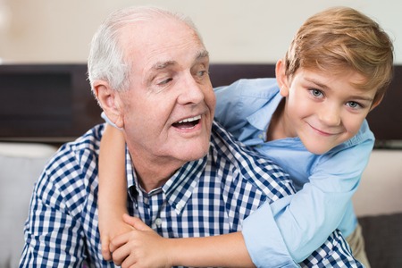 Happy little boy embracing senior grandfatherの写真素材