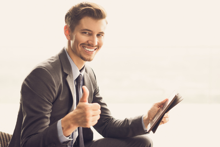 Smiling Young Businessman with Thumb Up and Tabletの写真素材