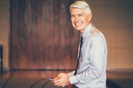 Smiling Senior Businessman Using Smartphoneの写真素材