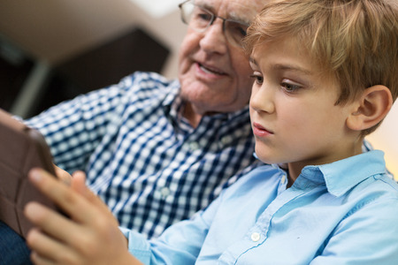 Focused Grandson and Grandfather Playing on Tabletの写真素材