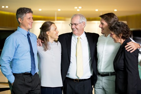 Smiling Senior Business Leader Embracing Coworkersの写真素材