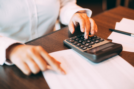 Businesswoman counting with calculator at tableの写真素材