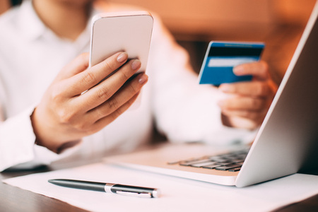 Female hand holding smartphone and credit cardの写真素材
