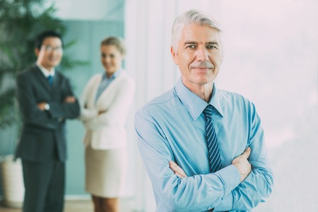 Confident senior businessman standing with his team